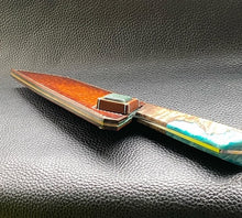 Load image into Gallery viewer, Hand dyed sunburst tan to brown Veg Tanned Leather outer with blue inserts and unique magnet securing mechanism. Fully handmade leather knife sheath which is completely hand stitched and hand finished to ensure the knife within is protected from the elements. We can design to our customer specifications to ensure you get a truly unique and bespoke item.www.leathercompositions.com
